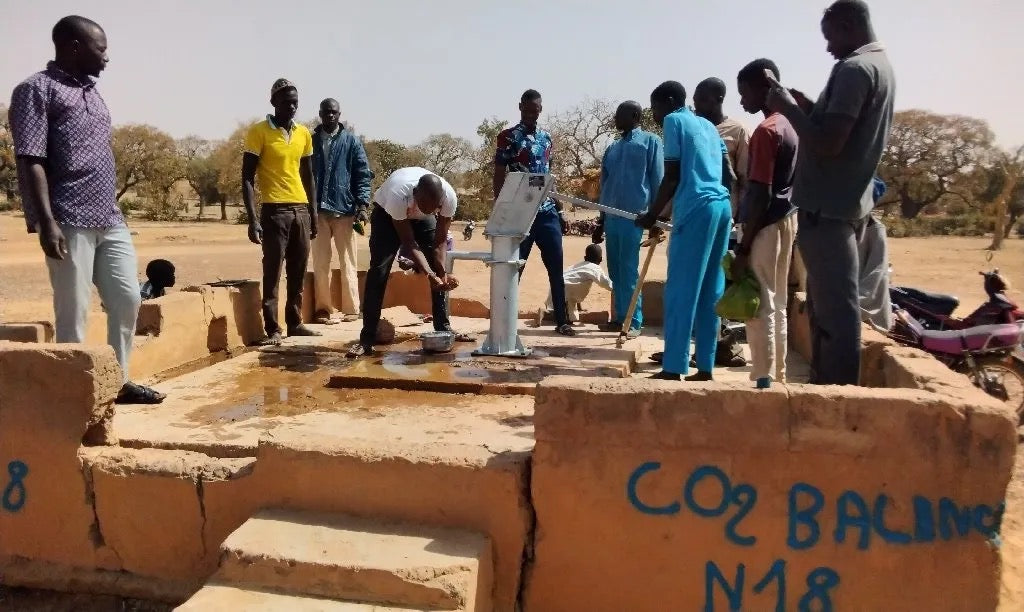 Community members and project staff at a rehabilitated borehole in Burkina Faso